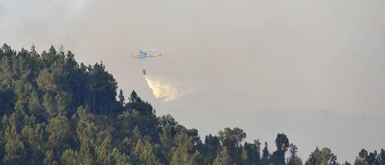 Un helicóptero interviene en un incendio en una masa boscosa de Vila de Cruces. // Bernabé/Javier Lalín