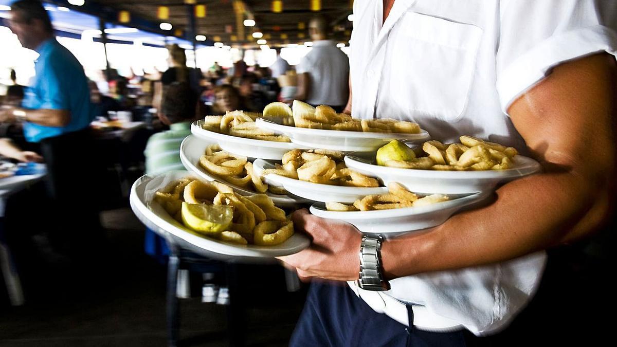 Un cambrer carregat de plats en un restaurant. | DDG