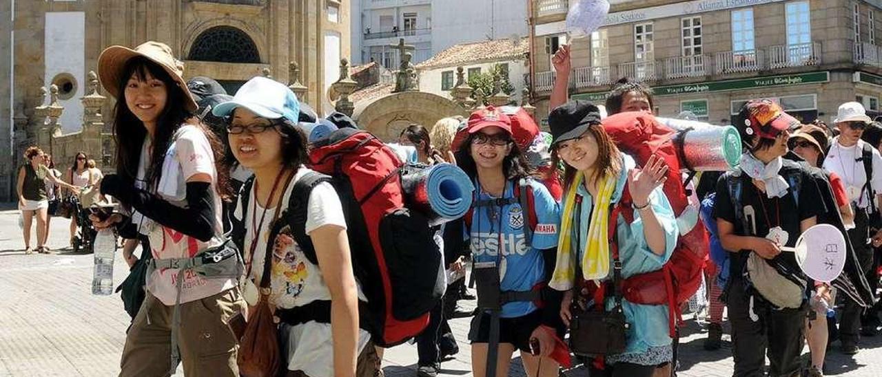 Jóvenes peregrinos asiáticos a su paso por la Praza da Peregrina. // Rafa Vázquez