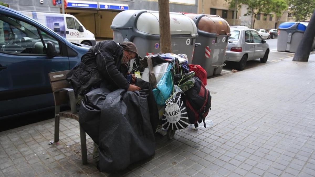 Un sintecho duerme en un banco de la calle de Vilà i Vilà, en el Poble Sec.