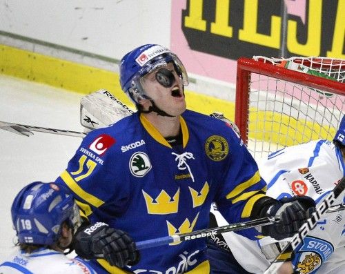 Carl Soderberg (Suecia) captura el 'puck' dentro de su casco cerca de la portería finesa durante un partido en el Malmo Arena