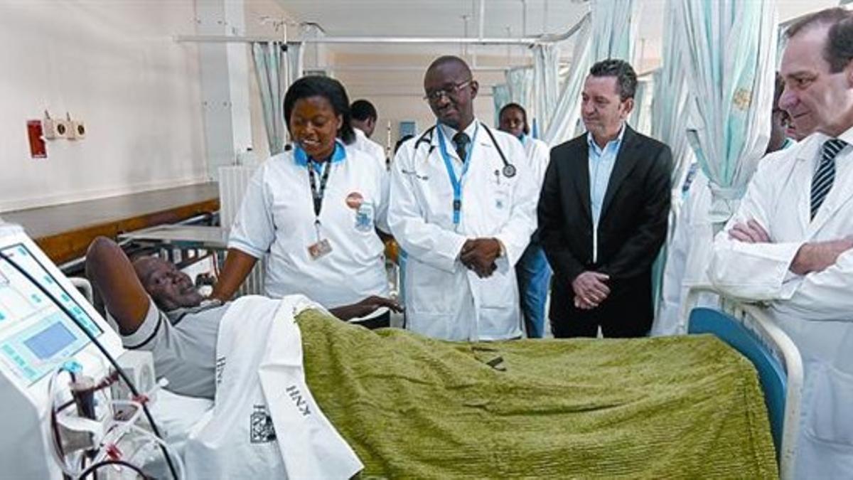 El doctor Federico Oppenheimer (derecha) y, a su lado, Francisco Ballester, director general de Novartis en España, visitan a un paciente en la sala de diálisis del Hospital Nacional de Kenia, la semana pasada.