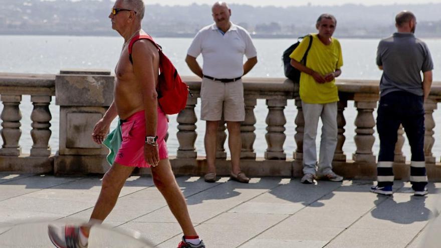 Un hombre, sin camiseta y con bañador, esta mañana en el Muro de San Lorenzo de Gijón.