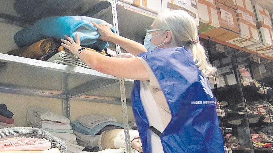 Una voluntaria coloca ropa en el ropero social del San Juan de Dios.