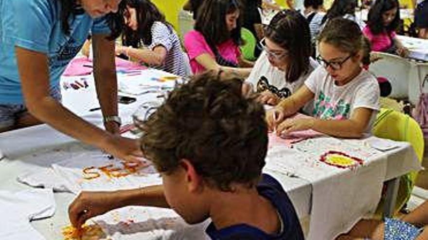 Una monitora enseña a los niños a decorar sus propias camisetas.