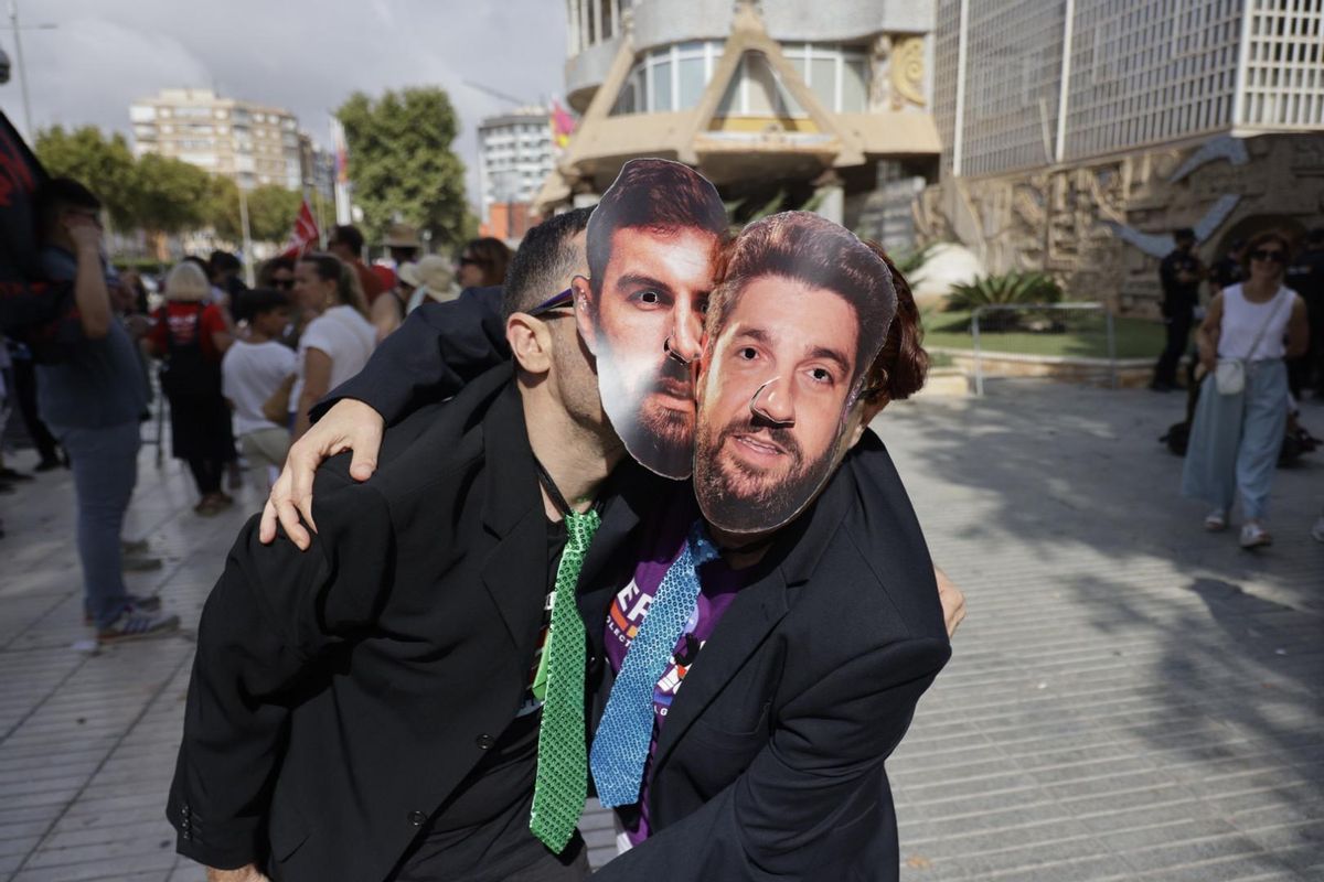 Dos manifestantes con las caretas de José Ángel Antelo (Vox) y Fernando López Miras (PP), a las puertas de la Asamblea Regional.