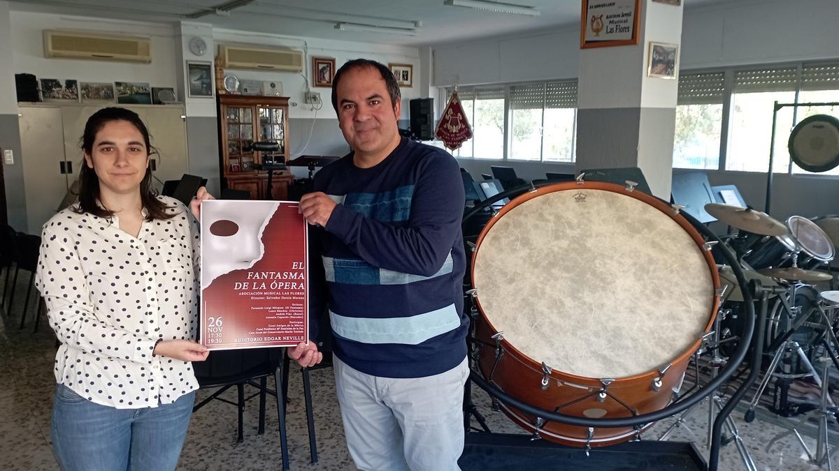 Ana Lucía Solano, presidenta de la Asociación Musical Las Flores y el director de la Banda de Música de Las Flores, Salvador García Moreno, con el cartel de ‘El fantasma de la ópera’, esta semana en la sala de ensayos.