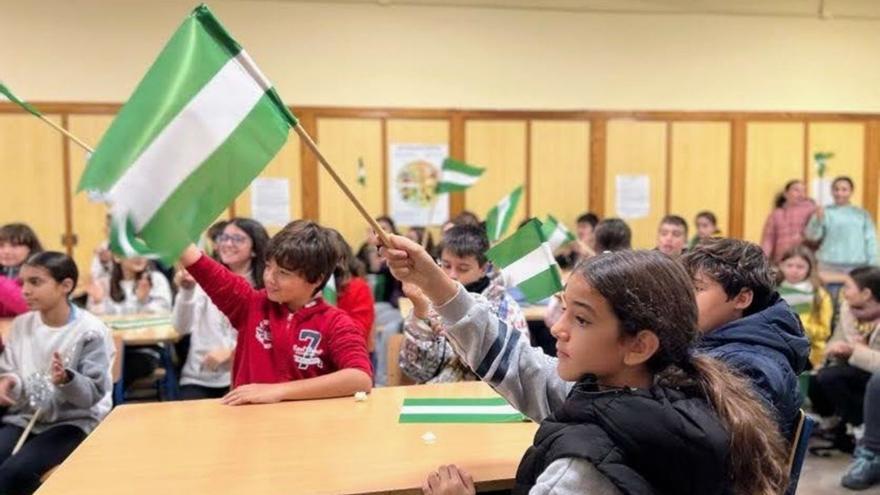 Un grupo de escolares enarbola las banderas andaluzas que han compuesto en el CEIP Santos Mártires.
