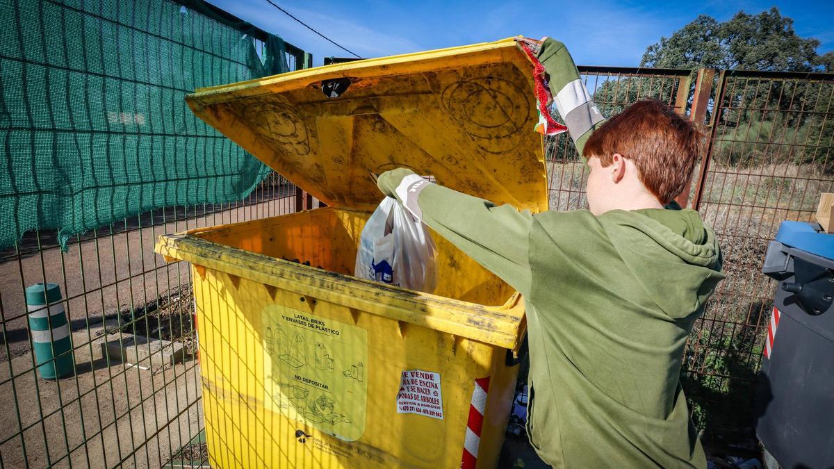 Un niño recicla correctamente en el contenedor amarillo.