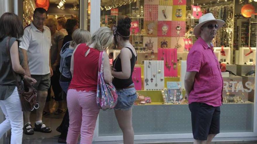 Un grupo de turistas delante de una tienda de la calle Real.