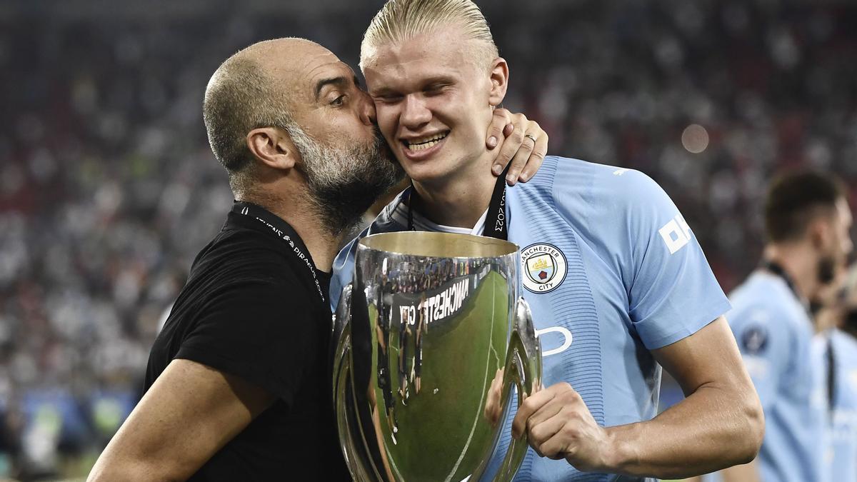 Manchester City's Spanish manager Pep Guardiola (L) kisses Manchester City's Norwegian striker #09 Erling Haaland after winning the 2023 UEFA Super Cup football match between Manchester City and Sevilla at the Georgios Karaiskakis Stadium in Piraeus on August 16, 2023. (Photo by Spyros BAKALIS / AFP)