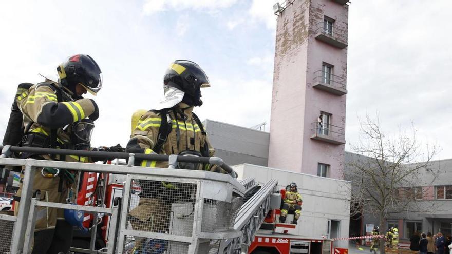 Bomberos en mitad de un simulacro usando su torre, al fondo, durante una exhibición el año pasado.