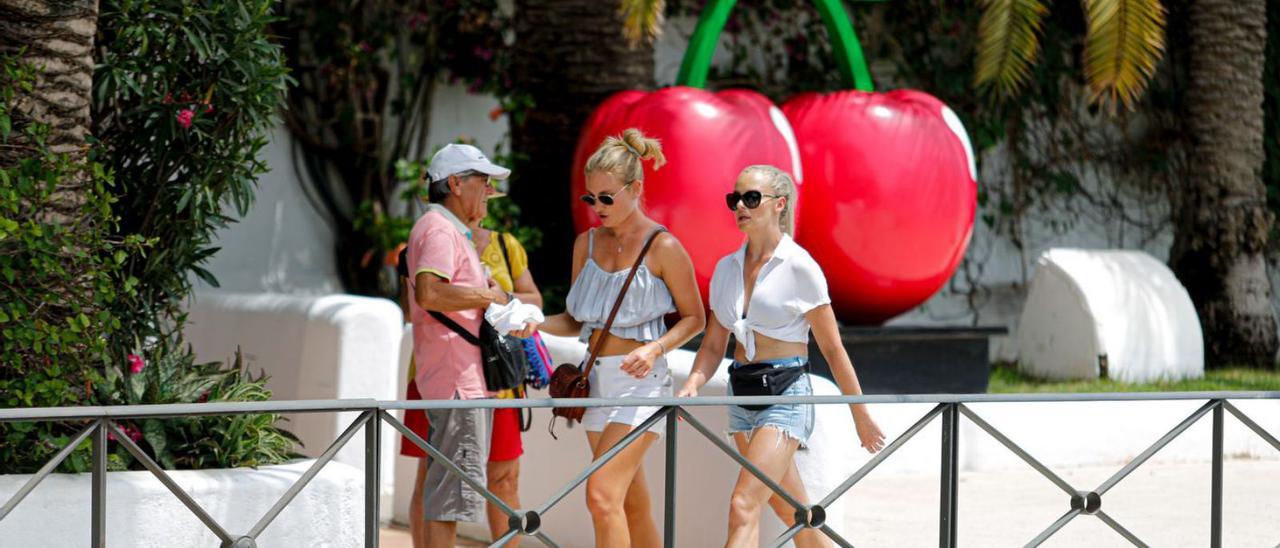 Turistas pasan frente a la discoteca Pacha con el símbolo de las cerezas en la entrada.