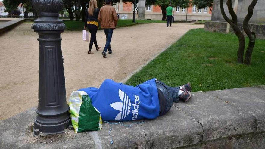 Un hombre sin hogar duerme en un muro en el centro de Pontevedra. // Gustavo Santos