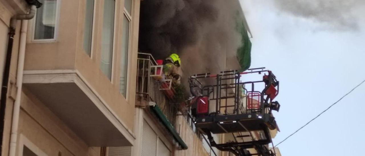 Los bomberos tratan de acceder a la vivienda en llamas.