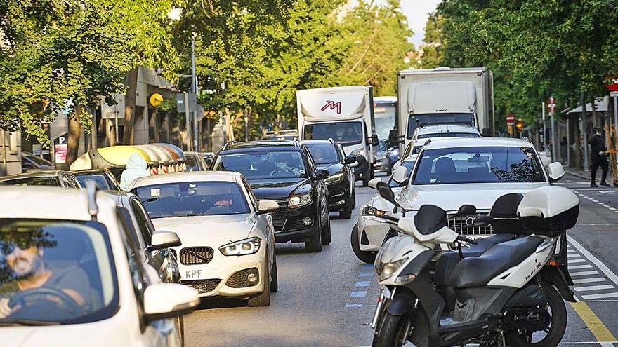 Vehicles entre contenidors i cotxes aparcats.