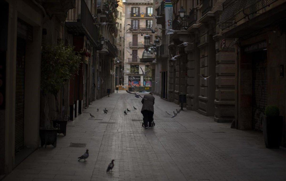 Una mujer empuja un carrito con sus pertenencias, en Barcelona.