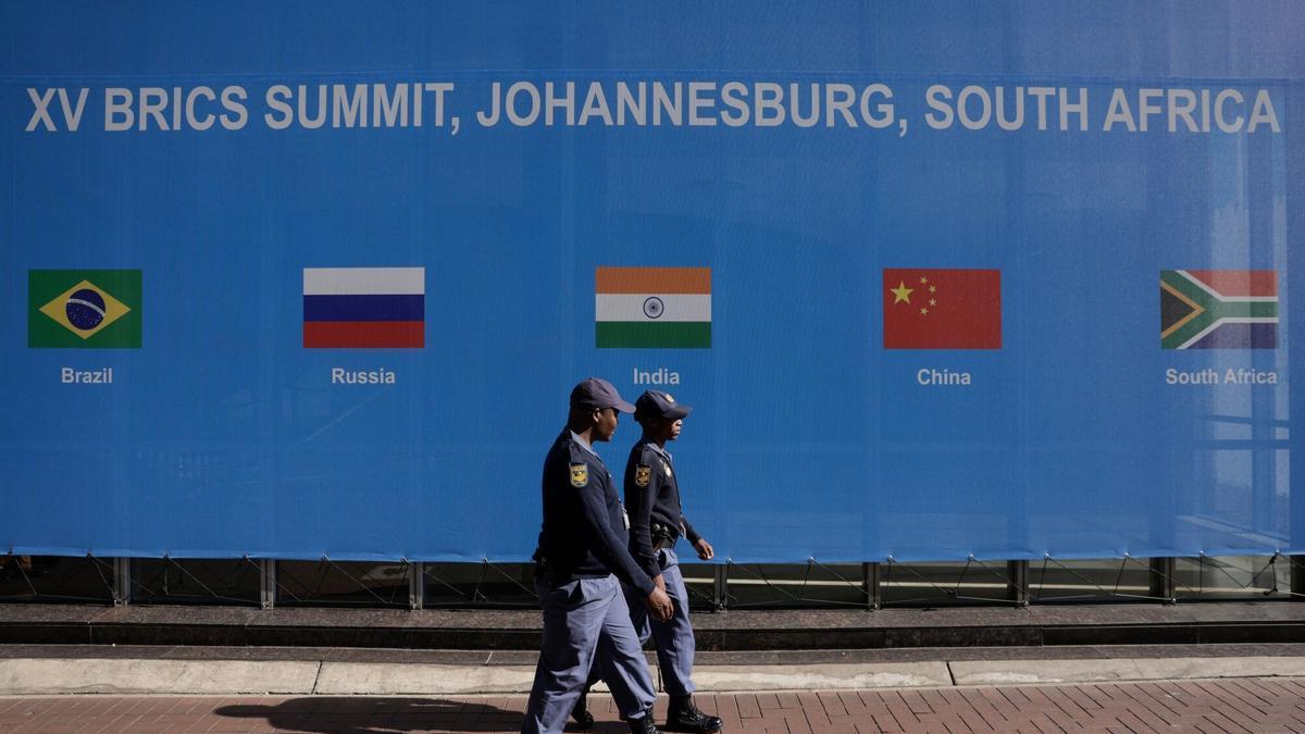 Dos agentes pasean frente a un mural de la cumbre de los BRICS en Sudáfrica.