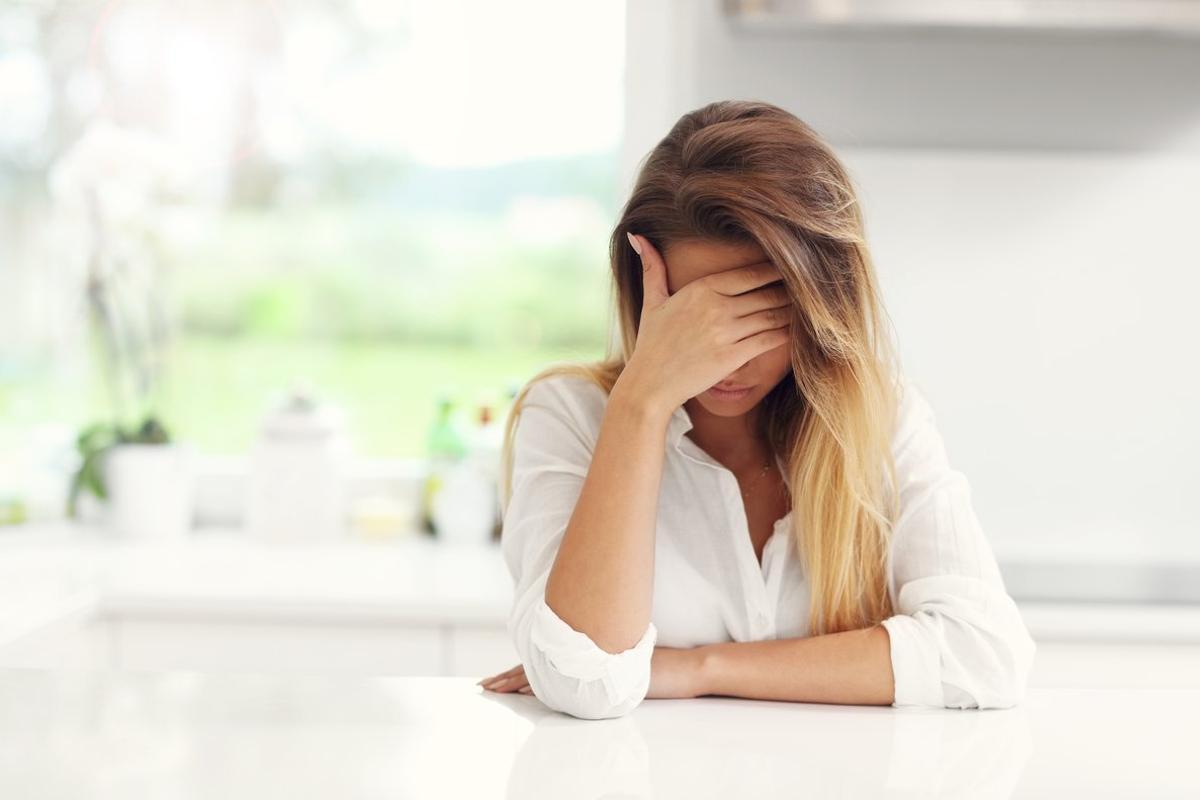 Mujer triste con la cara tapada.