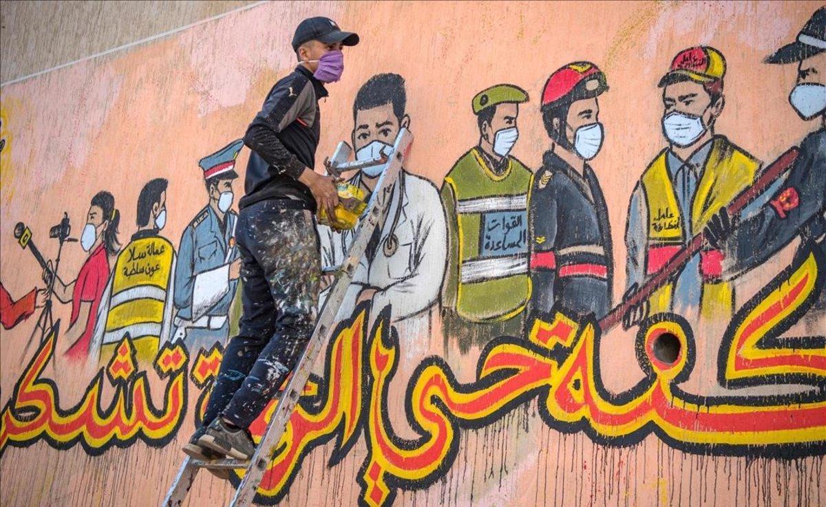Un artista local pinta un mural dedicado a los trabajadores esenciales durante la crisis del coronavirus, en Salé (Marruecos).