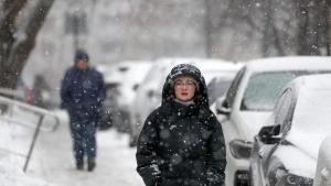 Una mujer camina bajo la nieve.