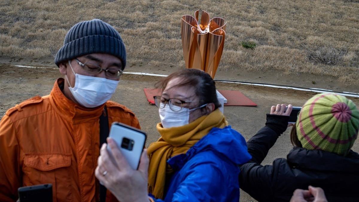 Ciudadanos japoneses se hacen fotos con la llama olímpica, recién llegada de Grecia, en Ishinomaki.