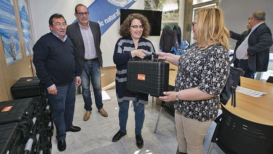 Domingo Ciurana y Miguel Ángel Picornell observan cómo Alícia Izquierdo entrega un desfibrilador.