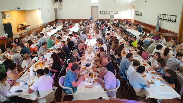 Vecinos y visitantes se sientan en una misma mesa para disfrutar de sus fiestas.