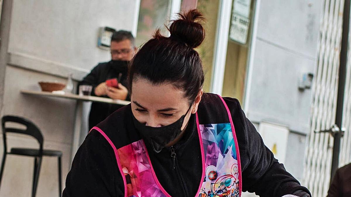 Una restauradora limpia una mesa tras la marcha de sus clientes.