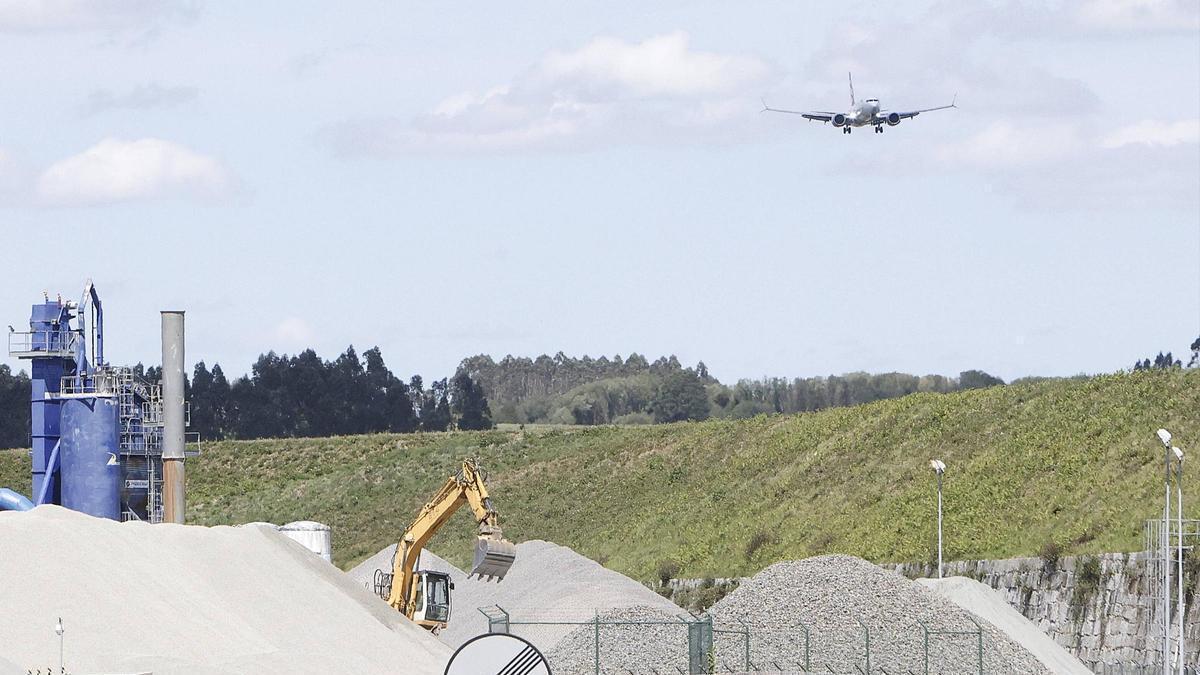 Uno de los últimos aviones que aterrizó este miércoles en el aeropuerto de Santiago antes de su cierre definitivo durante 35 días por las obras en la pista. En primer plano, la arenera que se ha improvisado junto a la infraestructura para la reposición del pavimento.