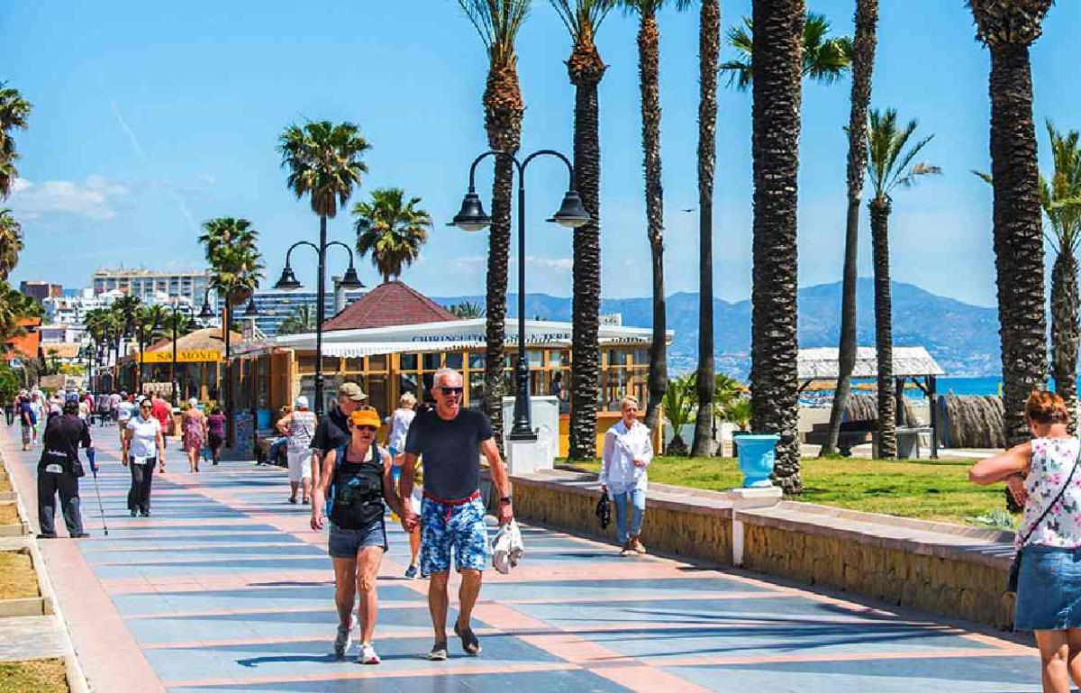 Turistas transitan por el paseo marítimo de una ciudad costera española.