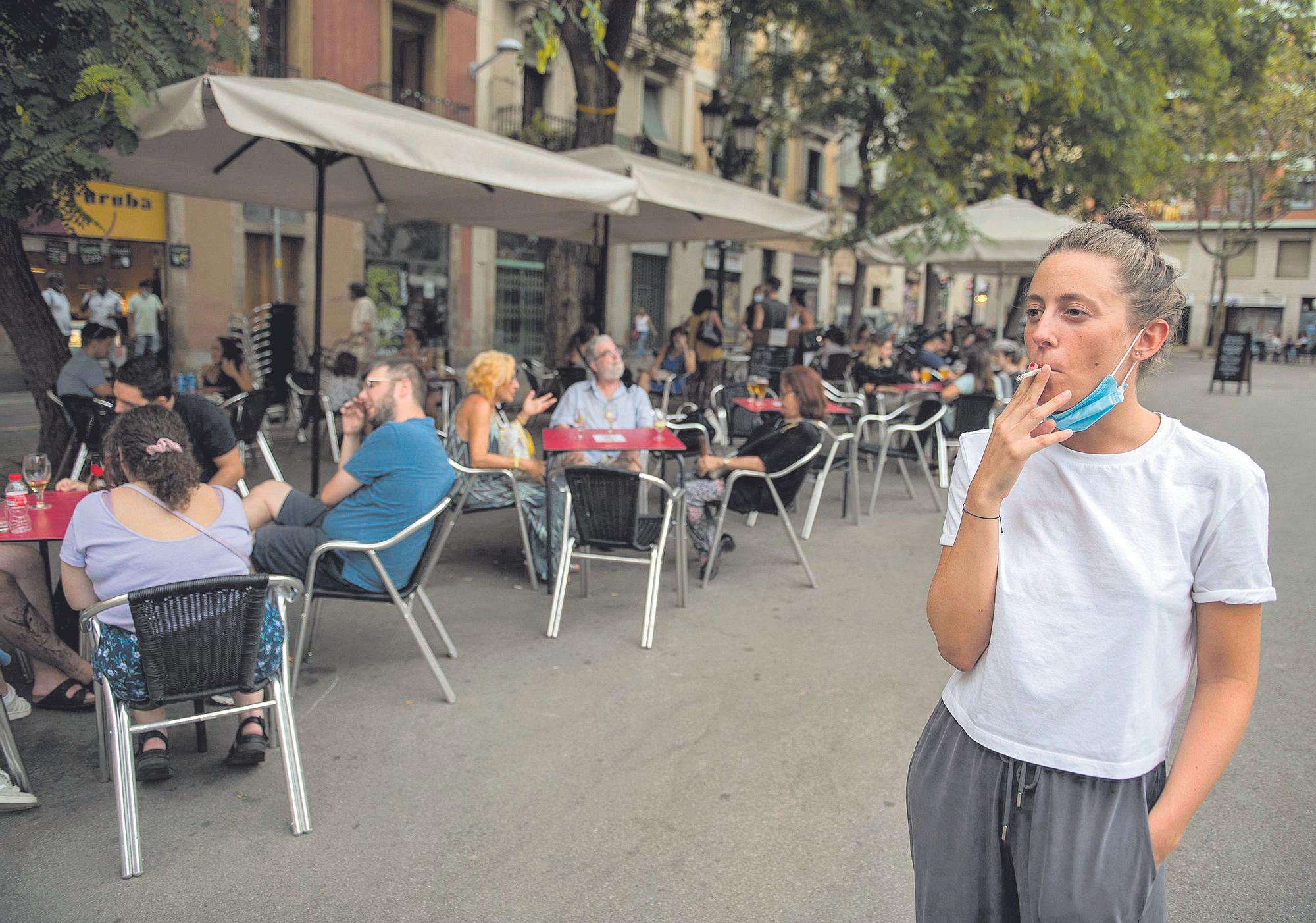 Una joven fuma al lado de una serie de terrazas, en Barcelona