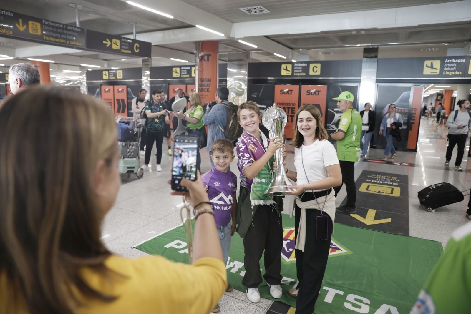 Medio centenar de aficionados reciben al Palma Futsal a su llegada a la isla tras conquistar la Champions