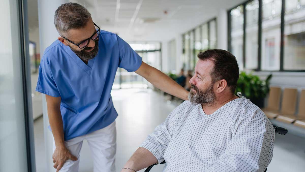 Un doctor y un paciente conversando en un pasillo de un hospital.