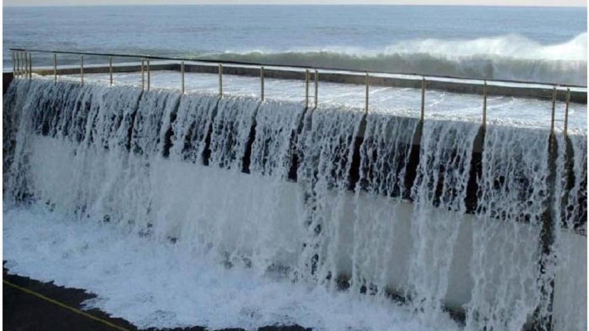 Olas rebasando el dique de abrigo del Port Olímpic.