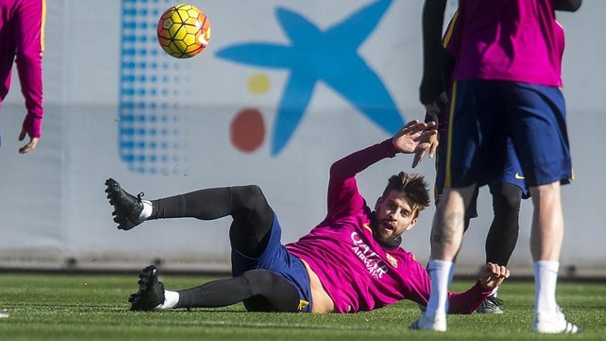 Piqué persigue el balón en el rondo durante el entrenamiento del Barça previo al duelo contra el Granada.