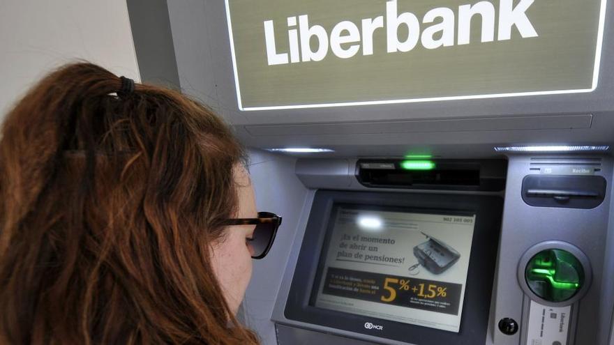 Una cliente saca dinero de un cajero de Liberbank.