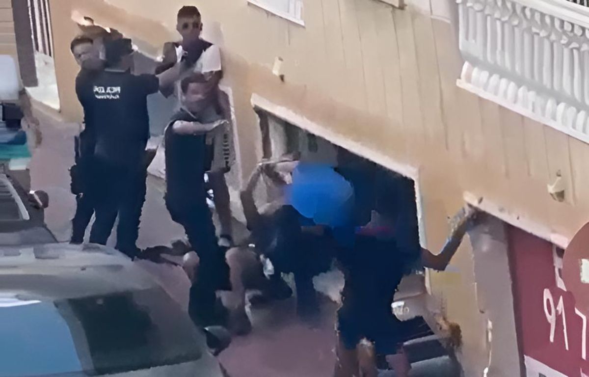 Uno de los miembros del grupo que increpaba a la policía les lanza un cubo