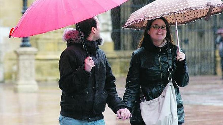 Dos turistas caminan bajo la lluvia, ayer, en Oviedo.