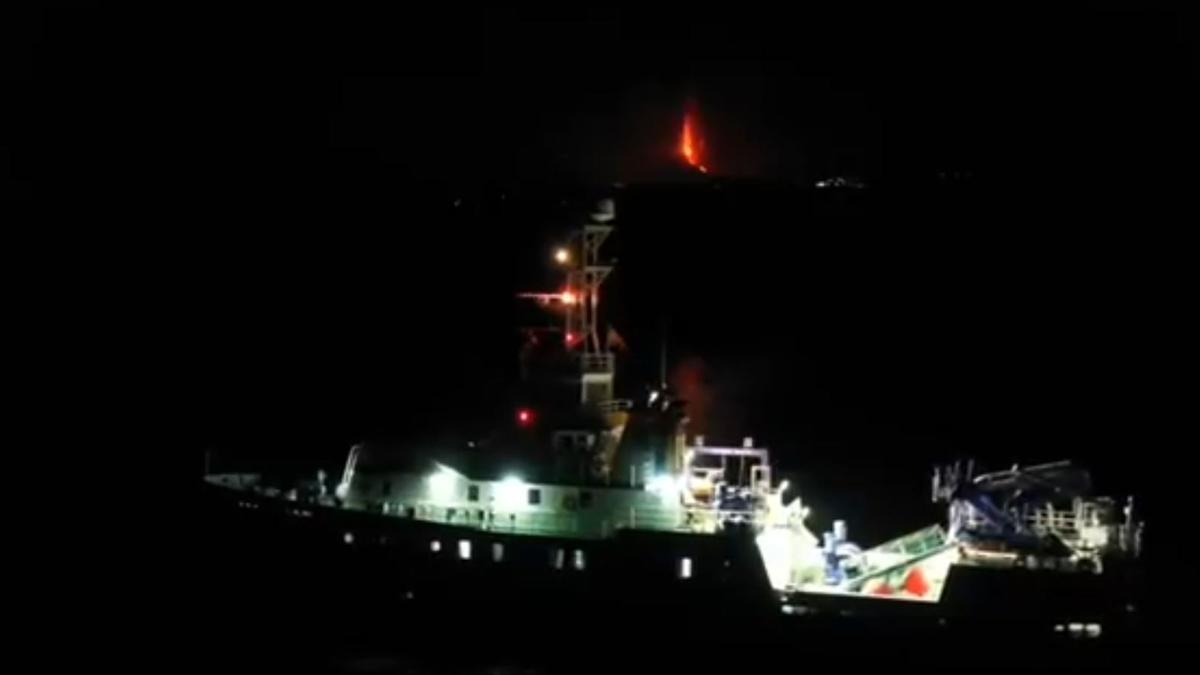 El buque 'Ramón Margalef' con la llama del volcán de La Palma al fondo.