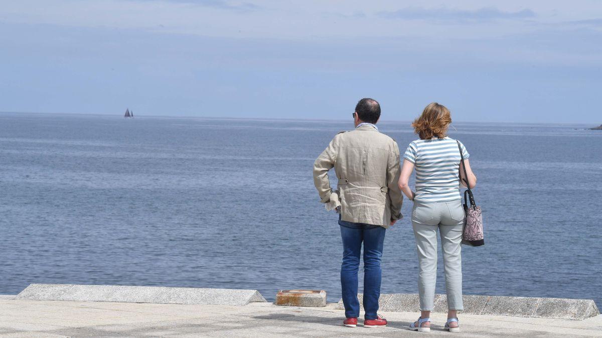 Dos personas observan el mar en el paseo marítimo de Riazor.