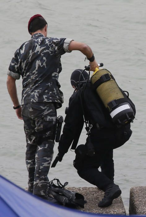 Los especialistas, que necesitan luz natural, trabajan en una zona balizada en un margen del río, apoyados por una lancha de la Policía Nacional, todo ello vigilado por agentes que impiden el acceso a la orilla de la dársena.