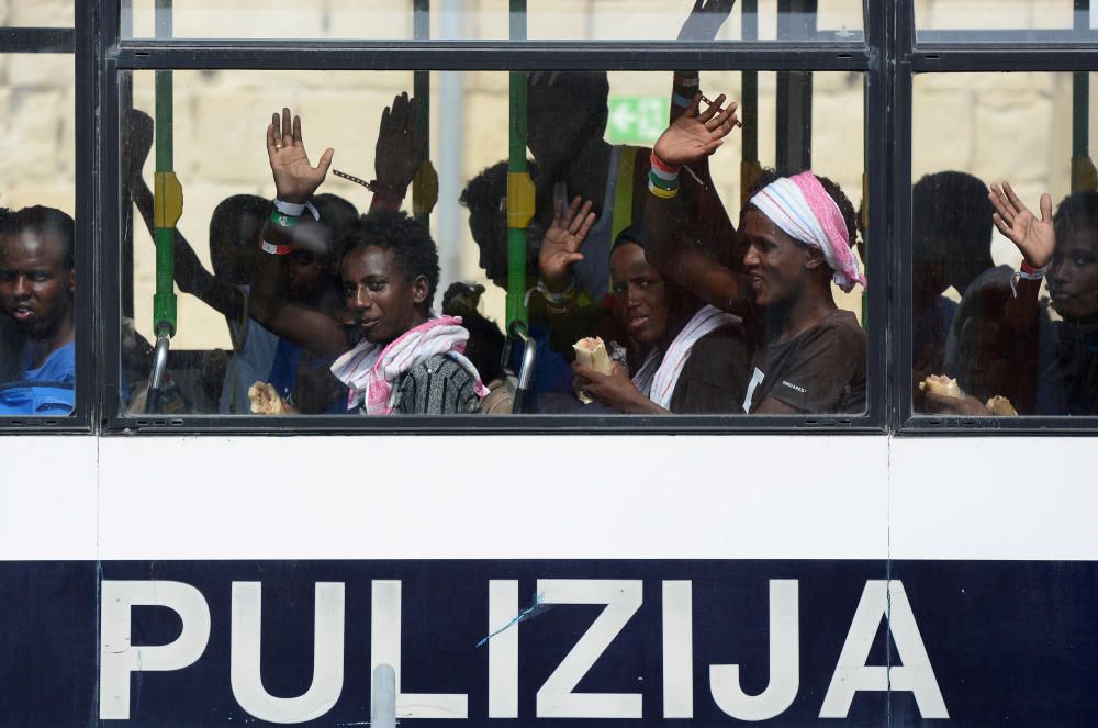 Los migrantes saludan desde el autobús después de desembarcar del MV Aquarius en el puerto de La Valeta, Malta.