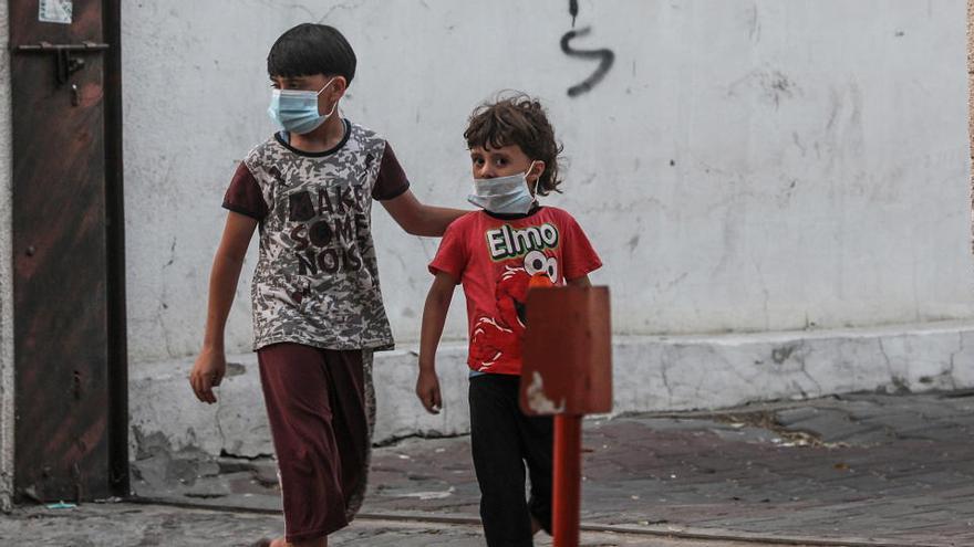 Dos niños palestinos con mascarilla, en Gaza