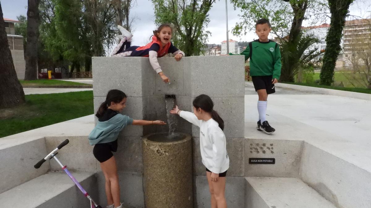 Niños en la fuente termal en la que el Concello ha instalado por ahora el cartel de &quot;no potable&quot;