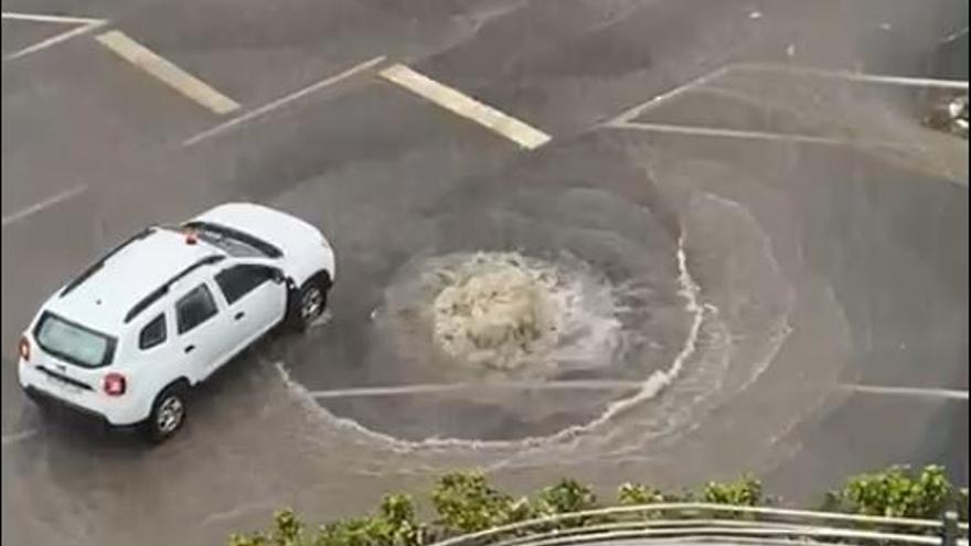 Un coche junto a una alcantarilla reventada en Guanerteme