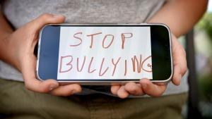 Un niño muestra en una pantalla de móvil un lema contra el bullying, en un colegio de Madrid.