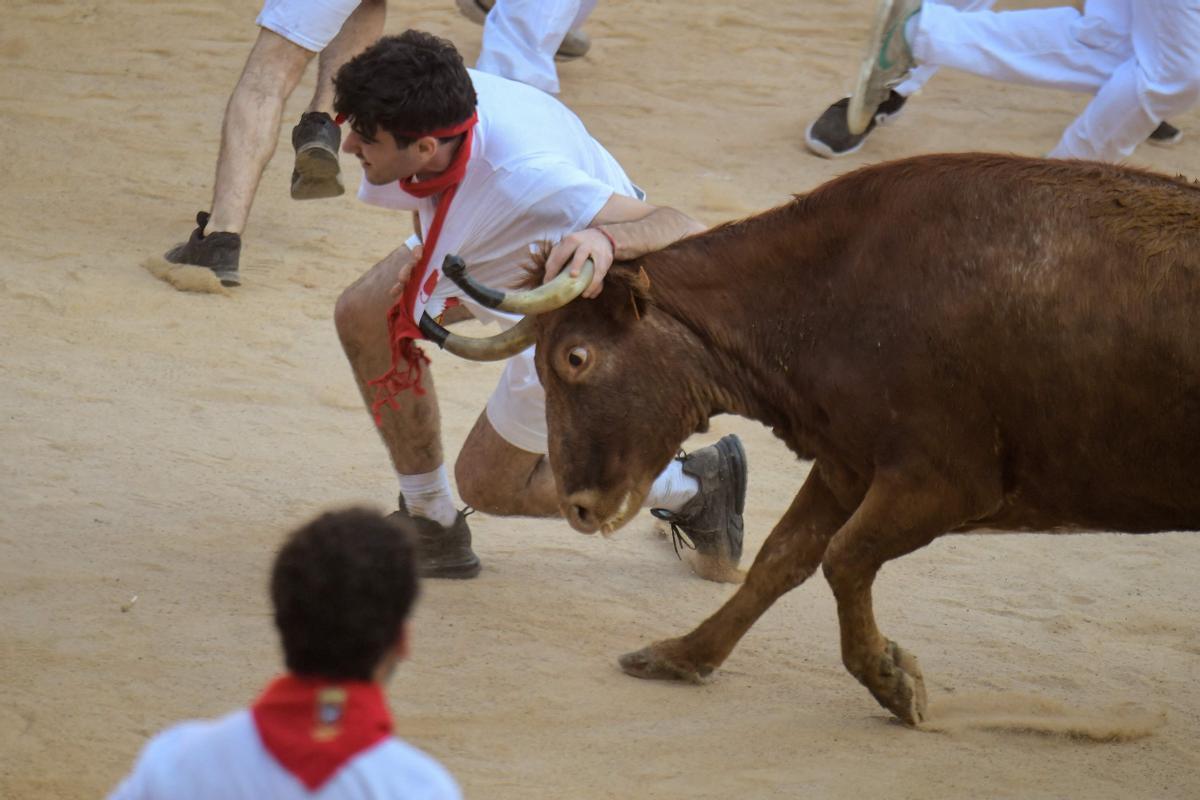 Un participante es derribado por una vaca joven después del encierro (corrida de toros) de las fiestas de San Fermín en Pamplona.