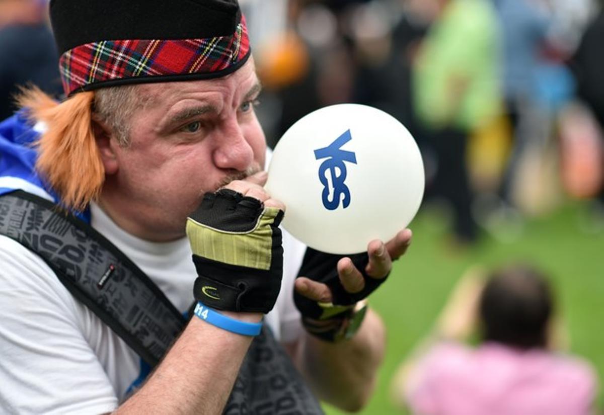 Un partidario del ’Yes’ infla un globo.