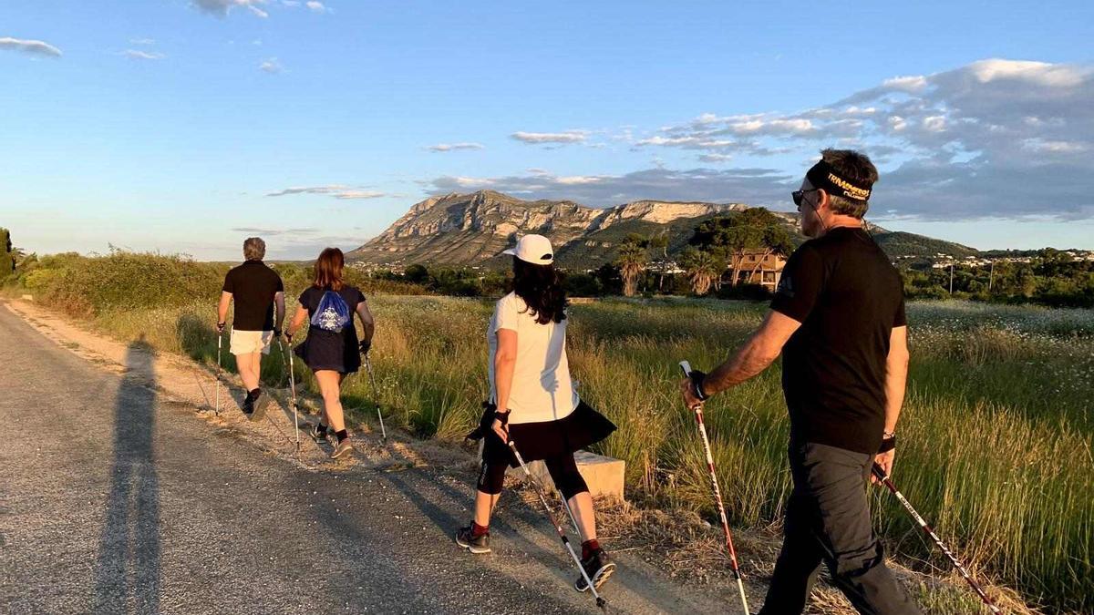 Los caminantes hacen ejercicio en un camino agrícola con el Montgó al fondo